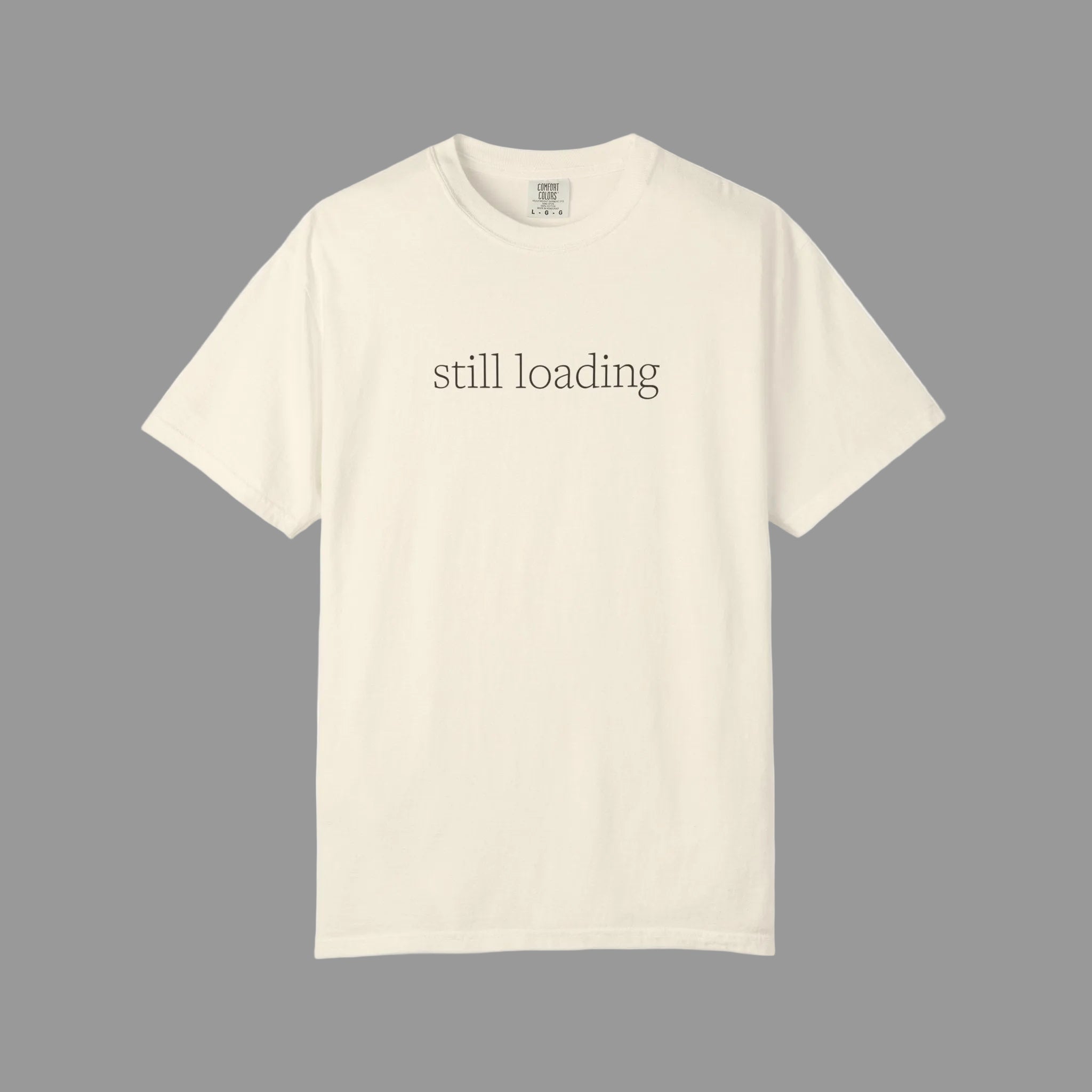 Beige t-shirt with 'still loading' text in espresso brown lettering